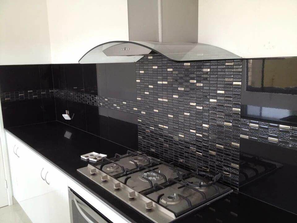 Modern kitchen featuring a black tile backsplash and a stainless steel stove