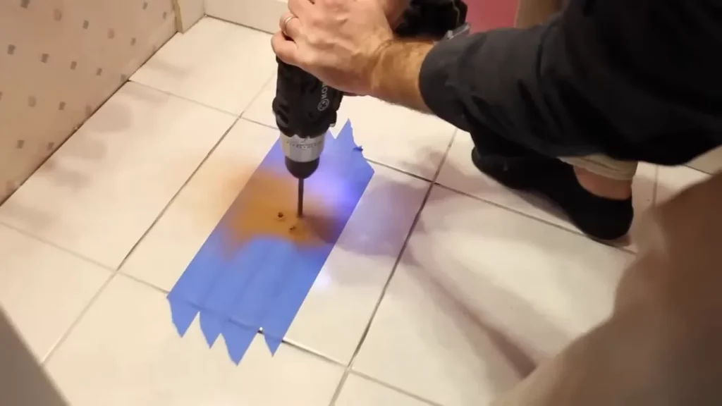 Using a drill to create pilot holes in the damaged tile for easier removal.