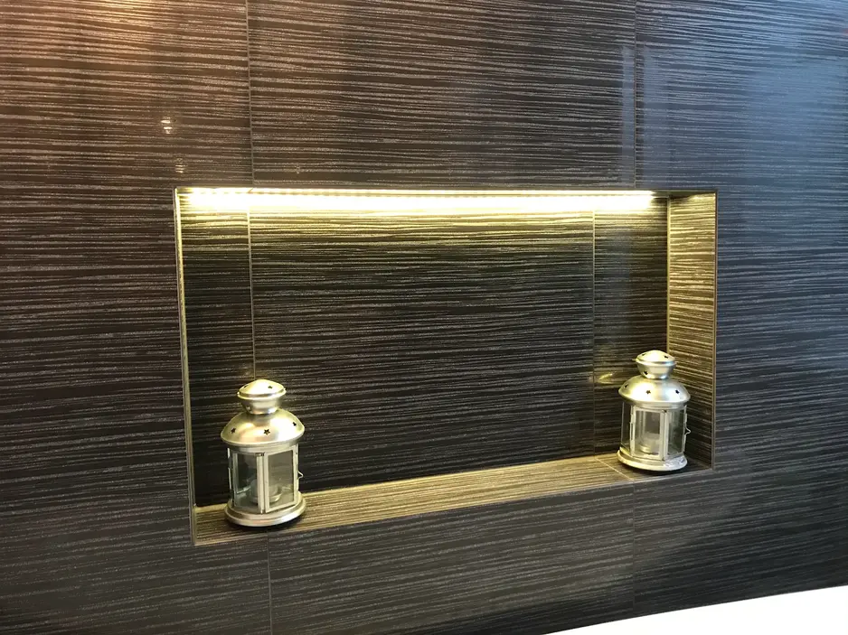 A modern bathroom tile niche with ambient LED lighting, featuring decorative silver lanterns for a stylish touch.