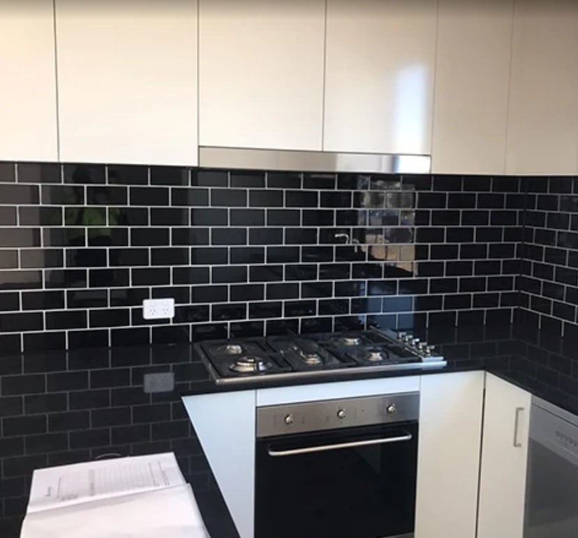 Modern kitchen with a black subway tile backsplash above a gas cooktop, professionally installed by a Sydney tiler